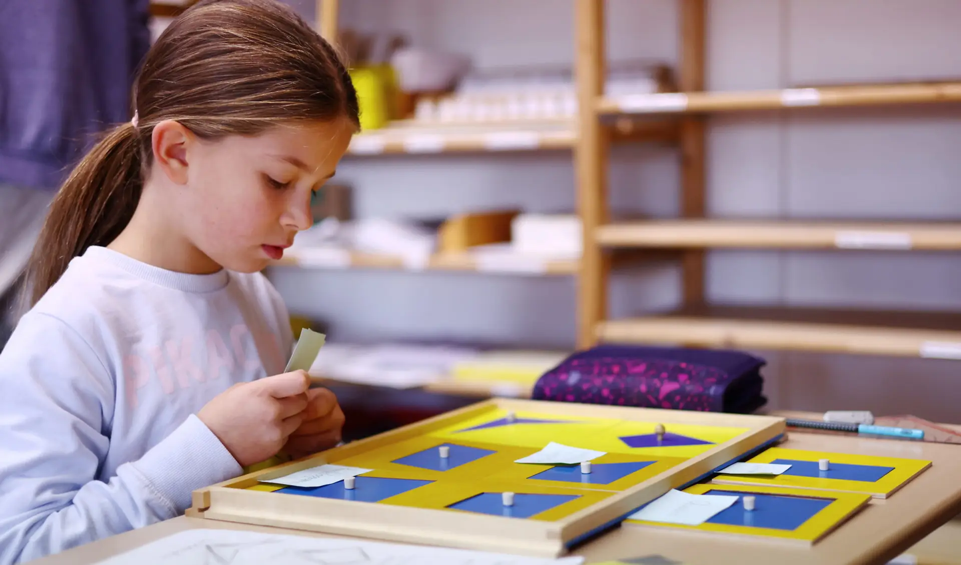 Schülerin arbeitet weiter mit Geometrie-Material und malt Formen aus.