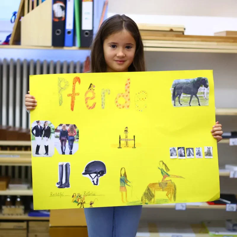 Schülerin zeigt ein Plakat zum Thema Pferde als Ergebnis eines Schulprojekts.