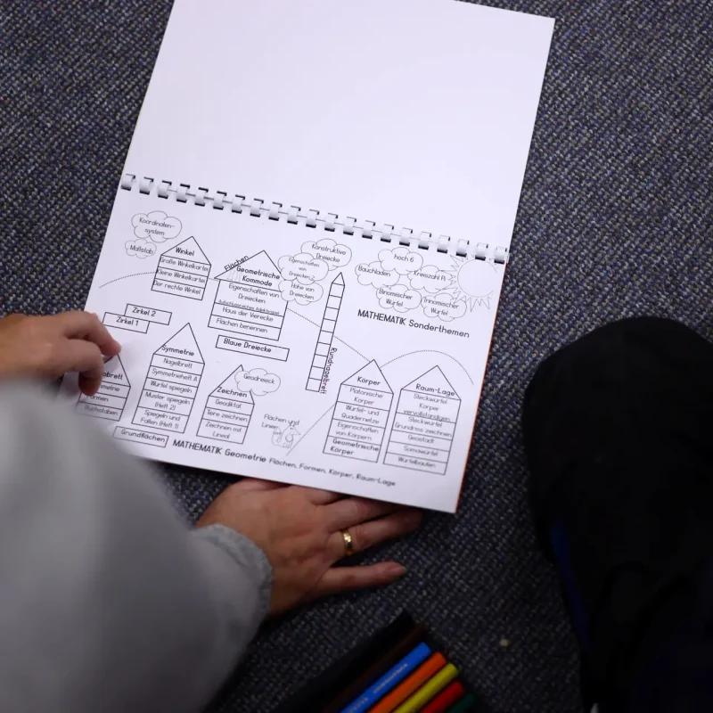 Schüler zeichnet mit Bleistift ein technisches Schema in sein Aufgabenheft.