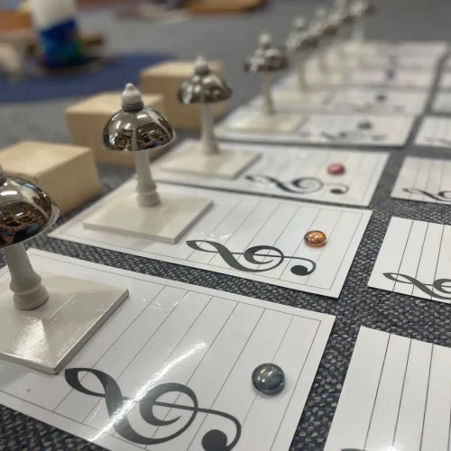 Montessori-Klangglocken liegen in einer Reihe auf einem Teppich, bereit zur Musikübung.