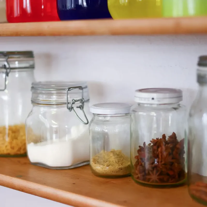 Regal mit verschiedenen Montessori-Gläsern gefüllt mit Materialien für Experimente und Sinnesübungen.