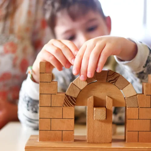Kind baut mit Holzbausteinen einen stabilen Bogen und entdeckt statische Prinzipien.