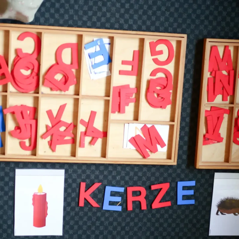 Holzbuchstaben und Bilderkarten bilden das Wort Kerze, Übung zum Lesenlernen.