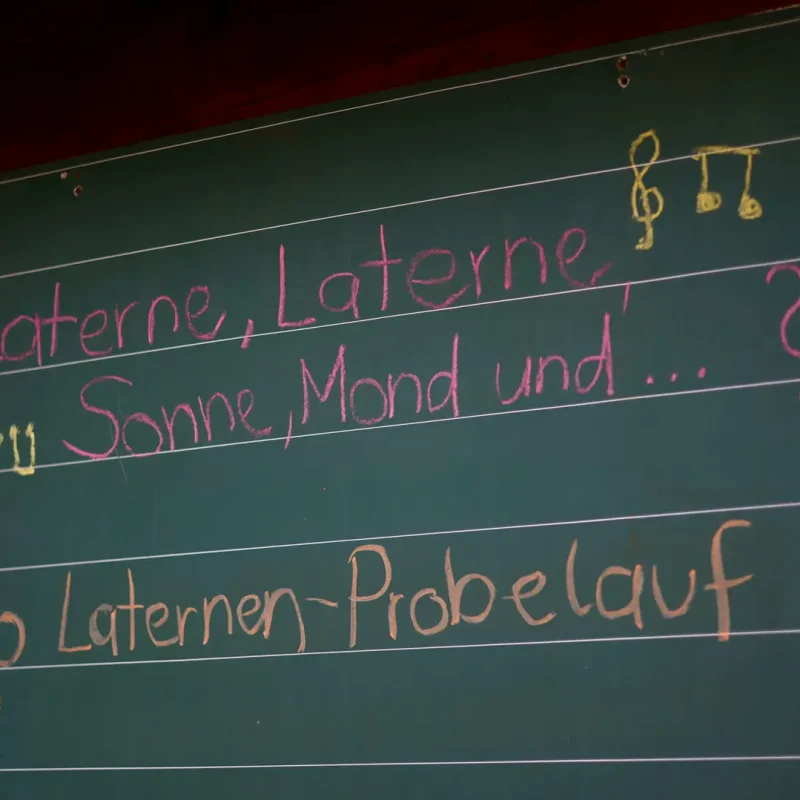 Tafel im Wald mit bunten Kreideschriften zu einem Montessori-Projekt oder Liedtext.