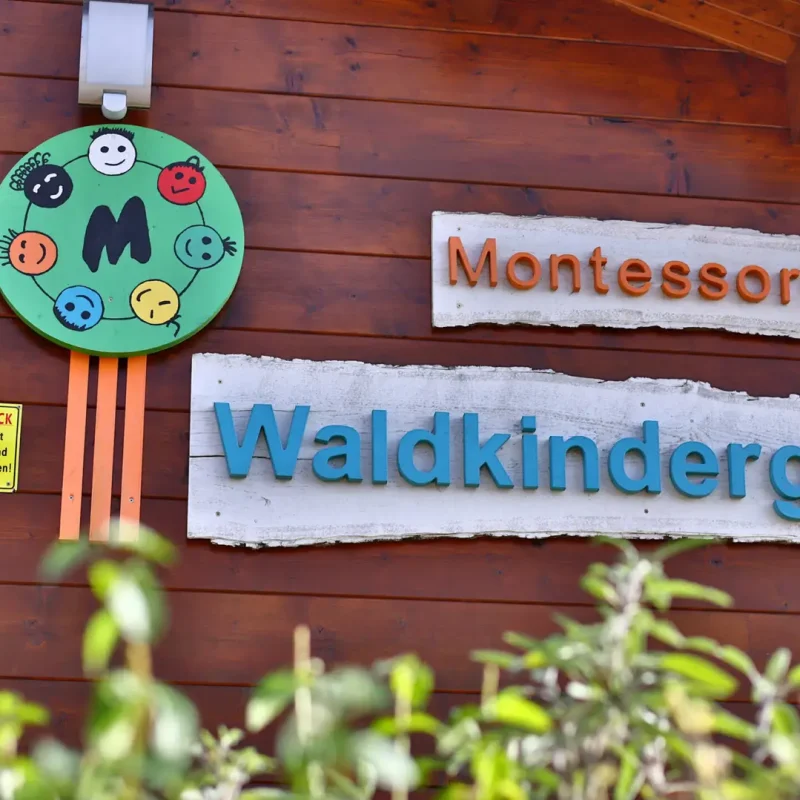 Eingangsschild des Montessori-Waldkindergartens an einer Holzwand.