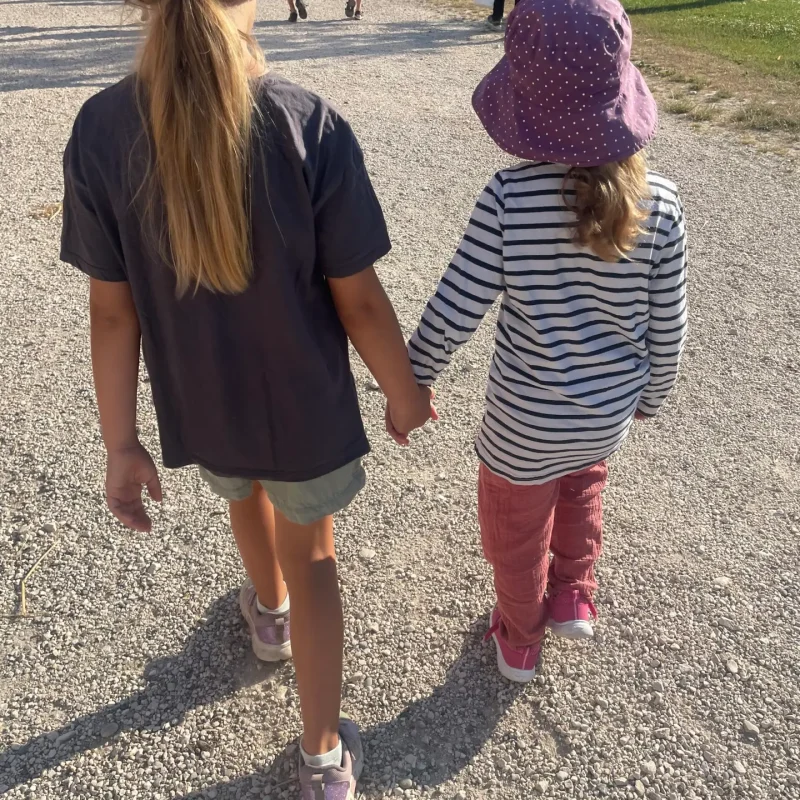 Zwei Kinder gehen gemeinsam einen Weg entlang und halten sich an den Händen.